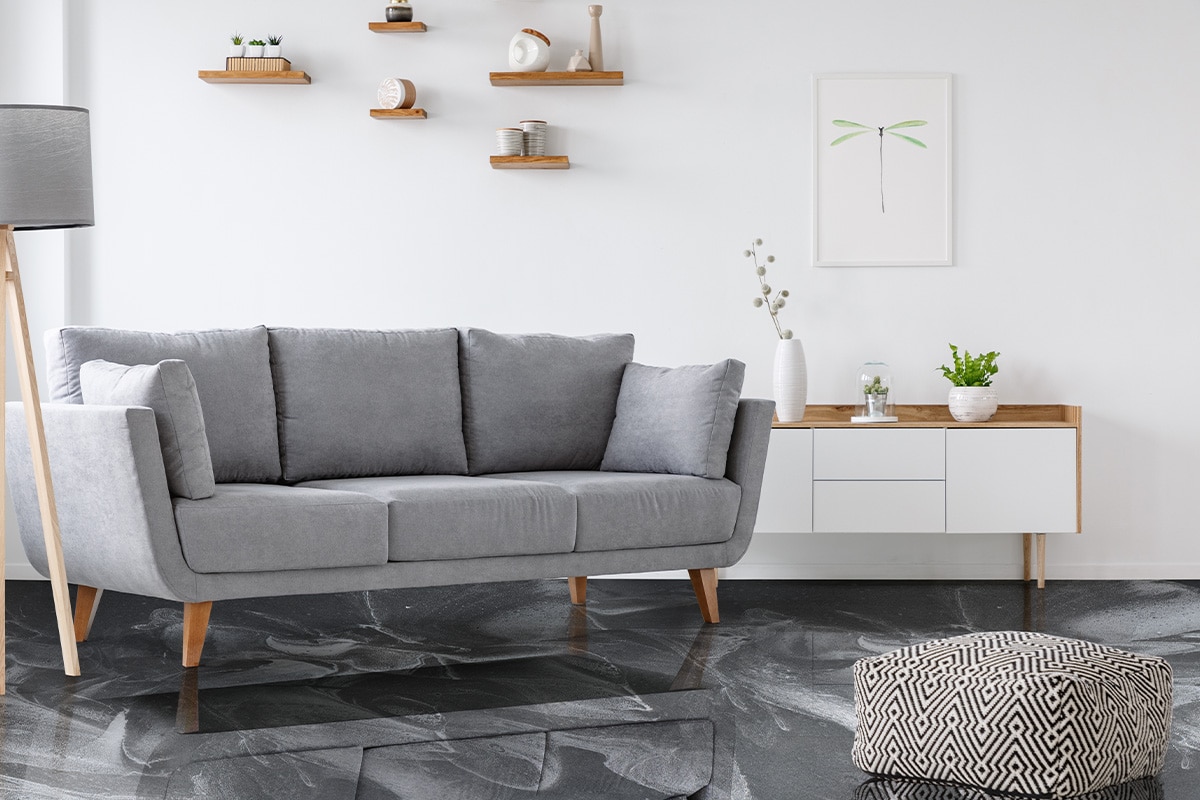 Patterned pouf and grey couch in minimal living room interior with poster above cupboard